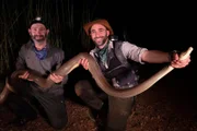 Mario and Coyote hold up a large python.