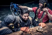 Unknown miner (back of head), Carlos Minor and James Hamm at the edge of the dive site. James Hamm prepares Carlos Minor‚Äôs dive gear.