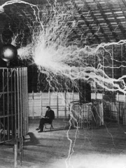 Erfinder und Wissenschaftler Nikola Tesla in seinem Labor, während sein Vergrößerungssender Hochspannungsgenerator Blitze von Elektrizität erzeugt. Dezember 1899.
