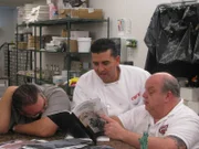 Frankie, Mauro and Buddy sit around table with State of Liberty figurine.