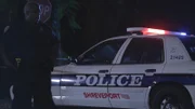 A cop stands by a cop car.