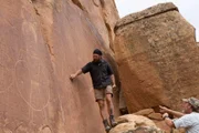 Chad Ollinger and Eric Drummond point out parts of the rock cliff drawings.