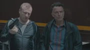 Weil John Zwart (Raymond Thiry, r.) Bob nicht vertraut, setzt er ihm mit Arek (Vitali Usanov) einen Aufpasser für die Fahrt nach Polen auf den Beifahrersitz.