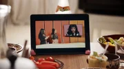Auf einem Tablet ist die Kultursendung zu sehen, in die Jo (Salka Weber) eingeladen worden ist. Von links: Moderation: Samira El Quassil, Expertin: Ciani-Sophia Höder und Jo (Salka Weber).