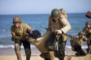 Kampfsanitäter Waverly Woodson Jr. (gespielt von Francesco Di Rauso) hilft, Verwundete in Sicherheit zu bringen, in einer Szene einer historischen Nachstellung des Zweiten Weltkriegs für "Erased: WW2's Heroes of Color". Waverly Woodson Jr. war ein Kampfsanitäter, der mit dem 320th Barrage Balloon Battalion am D-Day diente.