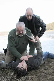Herzberger (Dietmar Huhn, l.) und Bonrath (Gottfried Vollmer) haben den scheinbar leblosen Ben (Tom Beck, lieg.) aus dem Wasser gezogen und wollen ihn wiederbeleben. Doch auf die Mund-zu-Mund-Beatmung will Ben gerne verzichten...