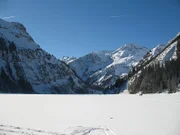 Im Winter ist der See dick zugefroren, so dass Skiläufer und Wanderer über ihn hinweg laufen.