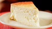 Der berühmte New-York-Käsekuchen von „Junior’s“ ist ein reichhaltiger, samtiger Vanillepuddingkuchen aus gesüßtem Frischkäse, der auf einer weißen Biskuitkruste gebacken wird.