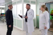 Silvio Vollinger (Martin Ontrop, li.) erkundigt sich besorgt nach seiner Frau, die nach einem schweren Autounfall in die Sachsenklinik eingeliefert wurde. Ihr Zustand ist äußerst kritisch und Dr. Roland Heilmann (Thomas Rühmann, mi.) muss sie operieren. Er bittet Schwester Miriam (Christina Petersen, re.), sich um Herrn Vollinger zu kümmern.