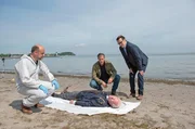 Die Leiche von Frank Loose (Arne Fuhrmann, liegend.) gibt den Kommissaren Finn Kiesewetter (Sven Martinek, 2.v.r.) und Lars Englen (Ingo Naujoks, r.) und Rechtsmediziner Dr. Henning Strahl (Christoph Tomanek, l.) einige Fragen auf.