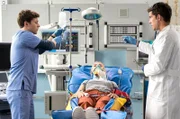Hella Kurtschik (Louise Sophie Arnold, M.) ist bei einem Krampfanfall die Treppe heruntergestürzt. Ben Ahlbeck (Philipp Danne, r.) und Florian Osterwald (Lion Wasczyk, l.) müssen schnell handeln, denn die Patientin droht an ihrem Zungenpiercing zu ersticken.