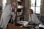 Sprechstundenhilfe Irena Bornholm (Nicole Beutler) verrät Dr. Roman Melchinger (Siegfried Rauch), dass sie sich wundert: Hat Martin Gruber etwa in der Praxis übernachtet?
