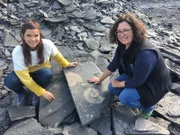 Auf einem Schieferbruch klopft Anna (links) mit Geologin Iris nach Fossilien. Sie finden zwei große Ammoniten.