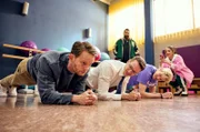 Sami (Ugur Kaya, hinten li.) und seine Tochter Sema (Acelya Sezer, hinten re.) schauen zu: Berti (Patrick Güldenberg, li.) lässt sich auf ein Plank-Battle mit Alexander (Vladimir Burlakov, 2. v. li.) und Roman (Helgi Schmid, 3. v. li.) ein.