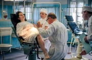 Im Kreißsaal: Prof. Dr. Kraatz (Uwe Ochsenknecht, 2.v.r.) untersucht die hochschwangere Christa Rosler (Muriel Bielenberg, li.), assistiert von Hebamme Witt (Zdenka Sajfertová, 2.v.l.).