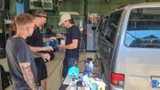 Drei Personen in einer Kfz-Werkstatt