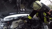 Feuerwehrleute überprüfen den Motor des Autos.