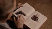 Kommissar Bent Isager-Nielsen blättert durch ein Buch, das die größten Kriminalfälle der skandinavischen Geschichte behandelt. Darunter auch der Fall zum ermordeten Nhut. Die Pistole aus dem Fall ist durch die jahrelange Lagerung im Wasser komplett verrostet.