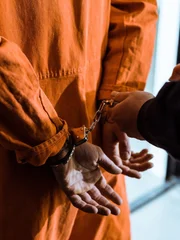 cropped image of prison officer wearing handcuffs on prisoner