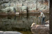 Landscape WS of Jeremy Wade casting from a rock ledge int still waters.  Location: New South Wales, Australia