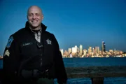 Officer Olson standing in front of a skyline.
