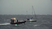 Segler im Sturm. Seenotretter versucht vom Tochterboot auf Havaristen überzusteigen.