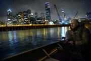 Officer Olson on a boat with a skyline behind him.