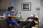 Dr. Lee plays her ukulele for Jerry Harrison post his cheek lipoma removal.