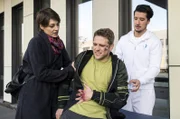 Der Skater Helge  (Silas Breiding, M.) taucht mit starken Schmerzen im Bauch im JTK auf. Dr. Theresa Koshka (Katharina Nesytowa, l. mit Komparse, r.) kümmert sich um den jungen Mann.