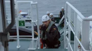 Ein Wachmann richtet eine Pistole auf ein Boot, während er einsteigt. (National Geographic)