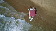 Eine Gruppe von Menschen schiebt ein gestrandetes Boot. (National Geographic)