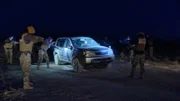 Autokontrolle in der Nacht; Polizisten umzingeln das Auto.