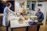 Hausmeister Fritz "Pflaster" (Uwe Preuss, r.) besucht Dr. Ella Wendt (Nina Gummich, l.) im Labor. Er hat sich bei der Arbeit am Finger verletzt.