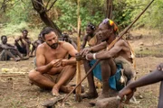 Hazen sitzt mit Hadza-Stammesangehörigen zusammen und betrachtet Pfeilspitzen.
