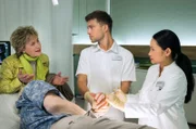 Hannelore Echtermeyer (Beatrice Richter, li.) hatte gerade eine Nachuntersuchung wegen ihres Brustkrebses in der Sachsenklinik, als ihr geliebter Mann Sven (Holger Franke, liegend) krampfend zusammengebrochen ist. Dr. Lilly Phan (Mai Duong Kieu, re.) und Pfleger Kris Haas (Jascha Rust, 2.v.re.) kümmern sich um das Ehepaar.