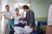 Jens Schmitt (Thomas Huber, liegend) wird mit einem Herzinfarkt eingeliefert. Dort nimmt ihn Dr. Maria Weber (Annett Renneberg, mi.) in Empfang. Begleitet wurde Jens von seinem Sohn Ruben (Jan-David Bürger, re.), der sich große Sorgen um seinen Vater macht. Li.: Komparse
