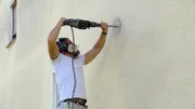 Mike Schopp bohrt die Außenwand für die Abzugshaube der Küche an.