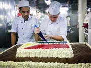 Schiffspraktikantin Laura Rotter und Crewmitglied Isaia bereiten die Torte für den Familien-Willkommens-Tag vor.