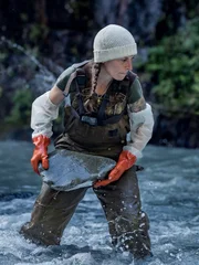 Kayla Johanson mit Schutzhandschuhen beim Steinwurf im Bach.