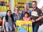 Kreuzfahrtdirektorin Manuela Bzdega, Reiseleiter Bernd und Entertainment-Manager Rainer Groeber besuchen das "Bahay Aruga", ein Haus für krebskranke Kinder, die sich im Philippine General Hospital (PGH) in Manila einer Behandlung unterziehen. Mayett Bonilla ist die Gründerin und Präsidentin von Bahay Aruga. Übergabe eine Bildes, das das Mädchen Kyzlmae gemalt hat.