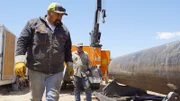 L-R: Juan Ibarra examining pipe, Freddy Dodge in background