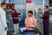 Dr. Matteo Moreau überprüft die Arbeit seines Assistenzarztes Olli Probst, als dieser den Patienten Izzy Pietz untersucht.
