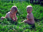 Zwei Babys sitzen im Gras.