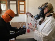 Mariana van Zeller (R) holding lab test tube with a masked subject.