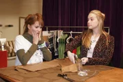 Hannah (Laura Osswald, l.) ist entsetzt, wie Kim (Lara-Isabelle Rentinck, r.) die Stoffteile zugeschnitten hat. Die ganze Arbeit ist umsonst und Kim merkt es wieder einmal nicht.