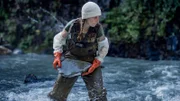 Kayla Johanson mit Schutzhandschuhen beim Steinwurf im Bach