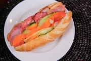 „Banh Mi“, ein französischer Beitrag zur vietnamesischen Küche, besteht aus Pastete, Mayonnaise und verschiedenen Aufschnitten, geschichtet auf einem weichen Baguette, garniert mit eingelegter Gurke, Karotte und Daikon, serviert hier im „Banh Mi Nguyen Sinh“ im Bezirk 1, Ho-Chi-Minh-Stadt.