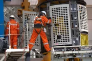 A crewmember precariously works on the ROV.