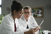 Elias (Stefan Ruppe, r.) zeigt Vivi (Jane Chirwa, l.) die Untersuchungsergebnisse von Ameena. Doch auch sie weiß keine Diagnose zu stellen.