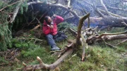 Host Bear Grylls eats an animal under a tree in the Cairngorm Mountain range, The Highlands of Scotland.